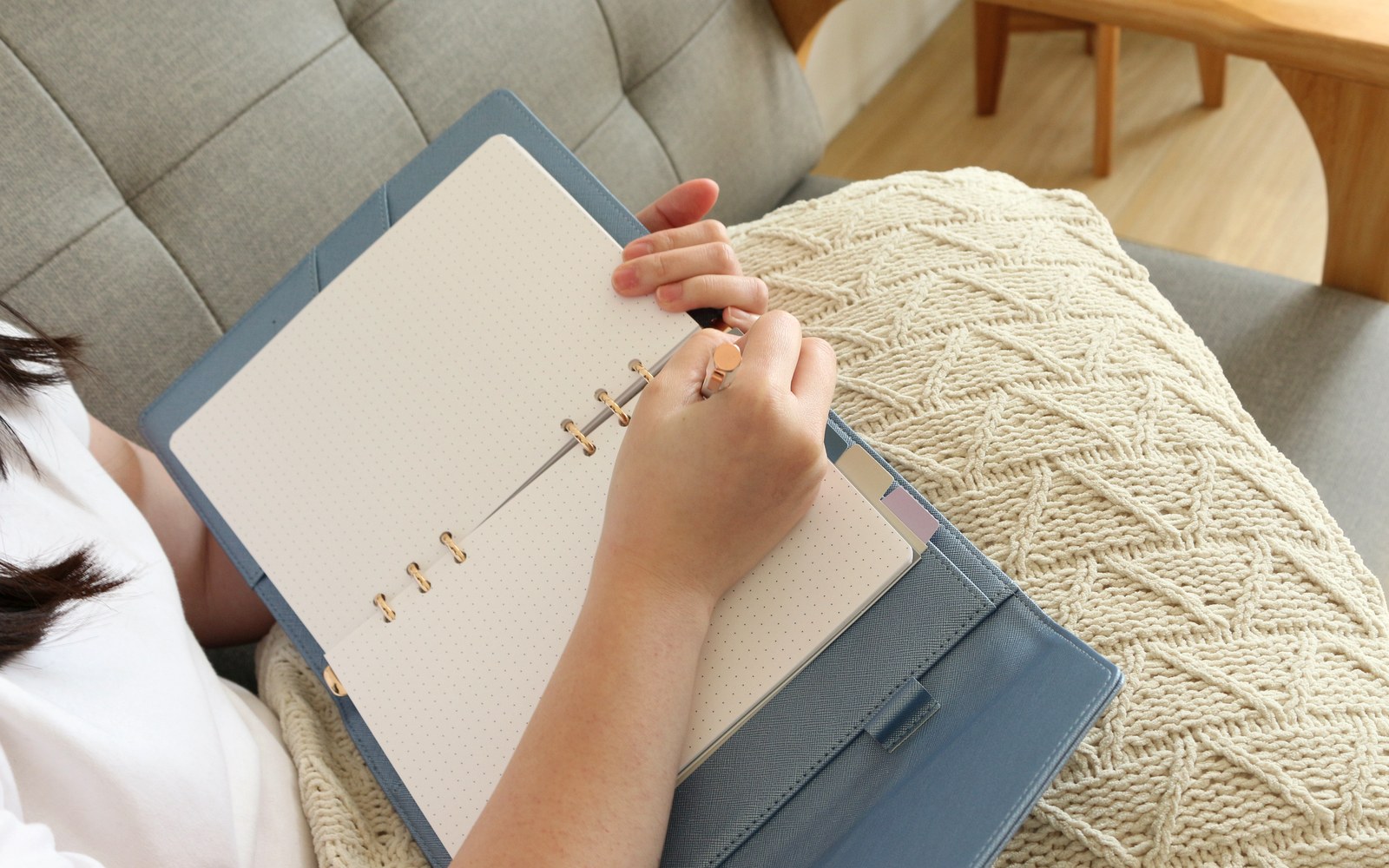 Writing in an EGOSUNNY planner on a cosy sofa