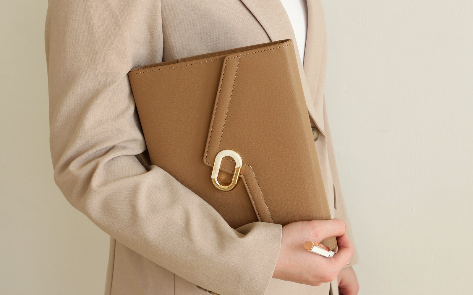 Woman in a beige blazer holding a tan EGOSUNNY L’Éclair planner