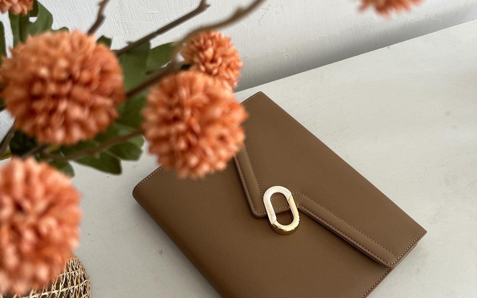 Brown EGOSUNNY L’Éclair planner beside a vase of orange flowers