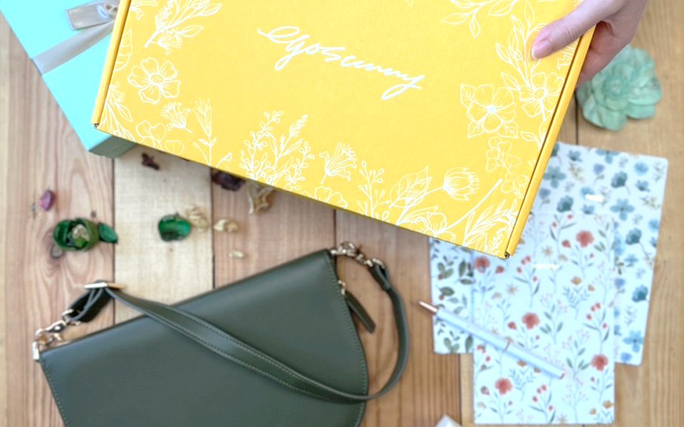 Olive EGOSUNNY Luna beside a yellow gift box and patterned paper