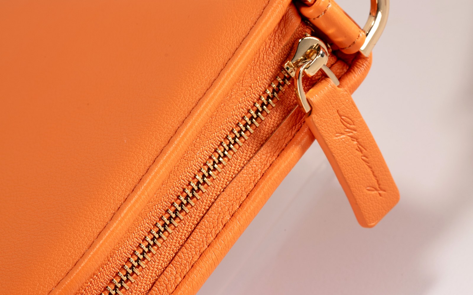 Close-up of the zip and strap on an orange EGOSUNNY Luna