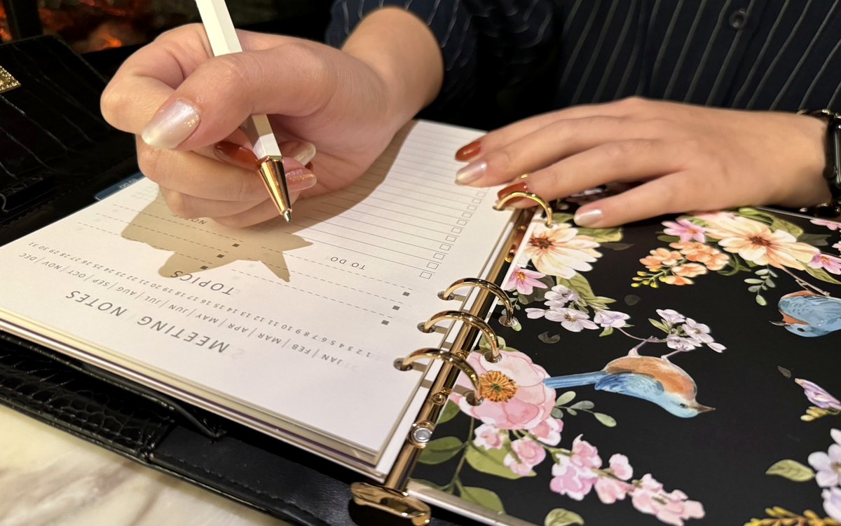 Hand writing in an EGOSUNNY planner with a floral divider page