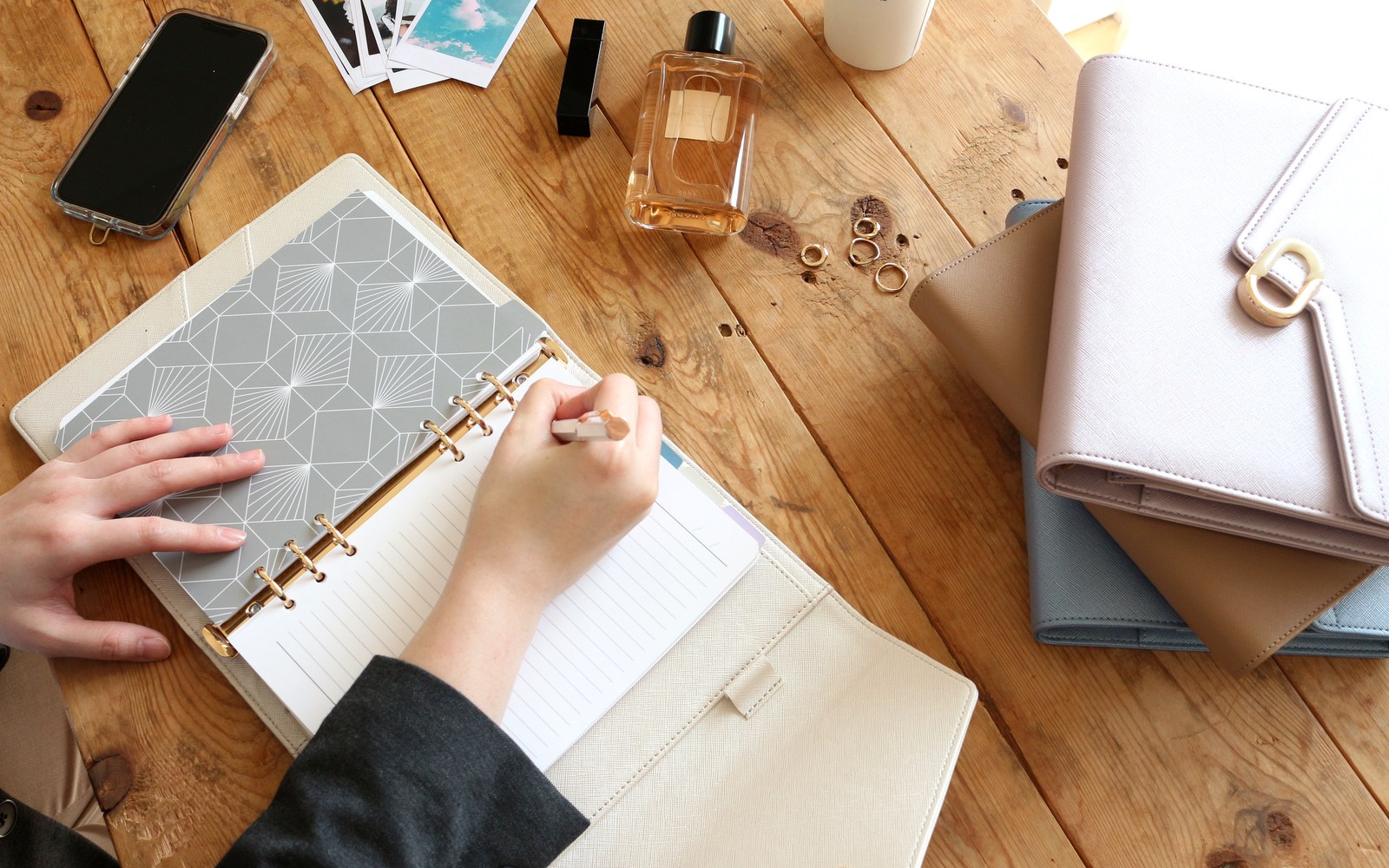 Hands writing in an EGOSUNNY planner beside a stack of planners