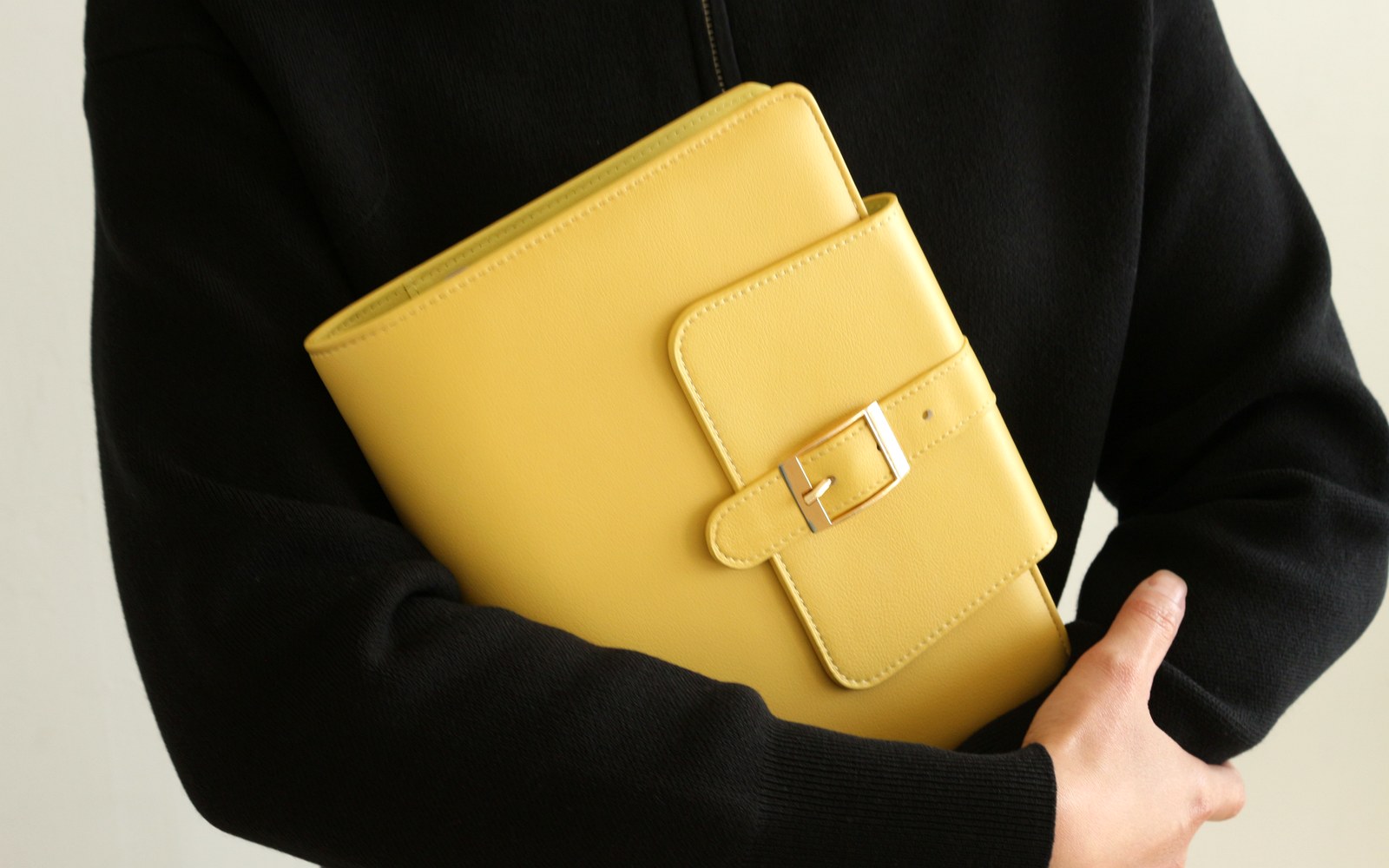 Woman holding a yellow EGOSUNNY Belt planner against a black outfit