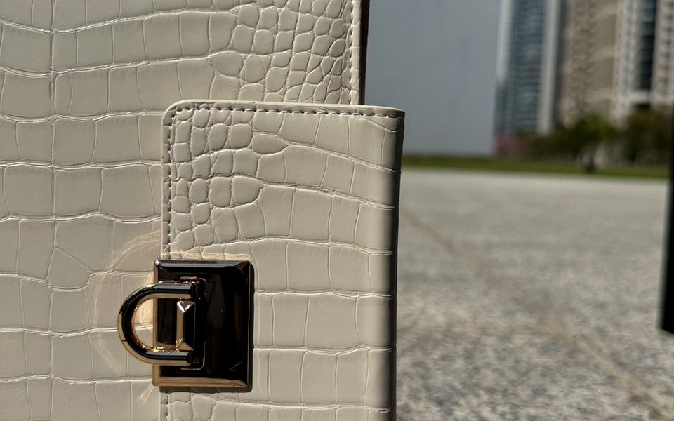 Cream EGOSUNNY Croco planner held up against a city backdrop
