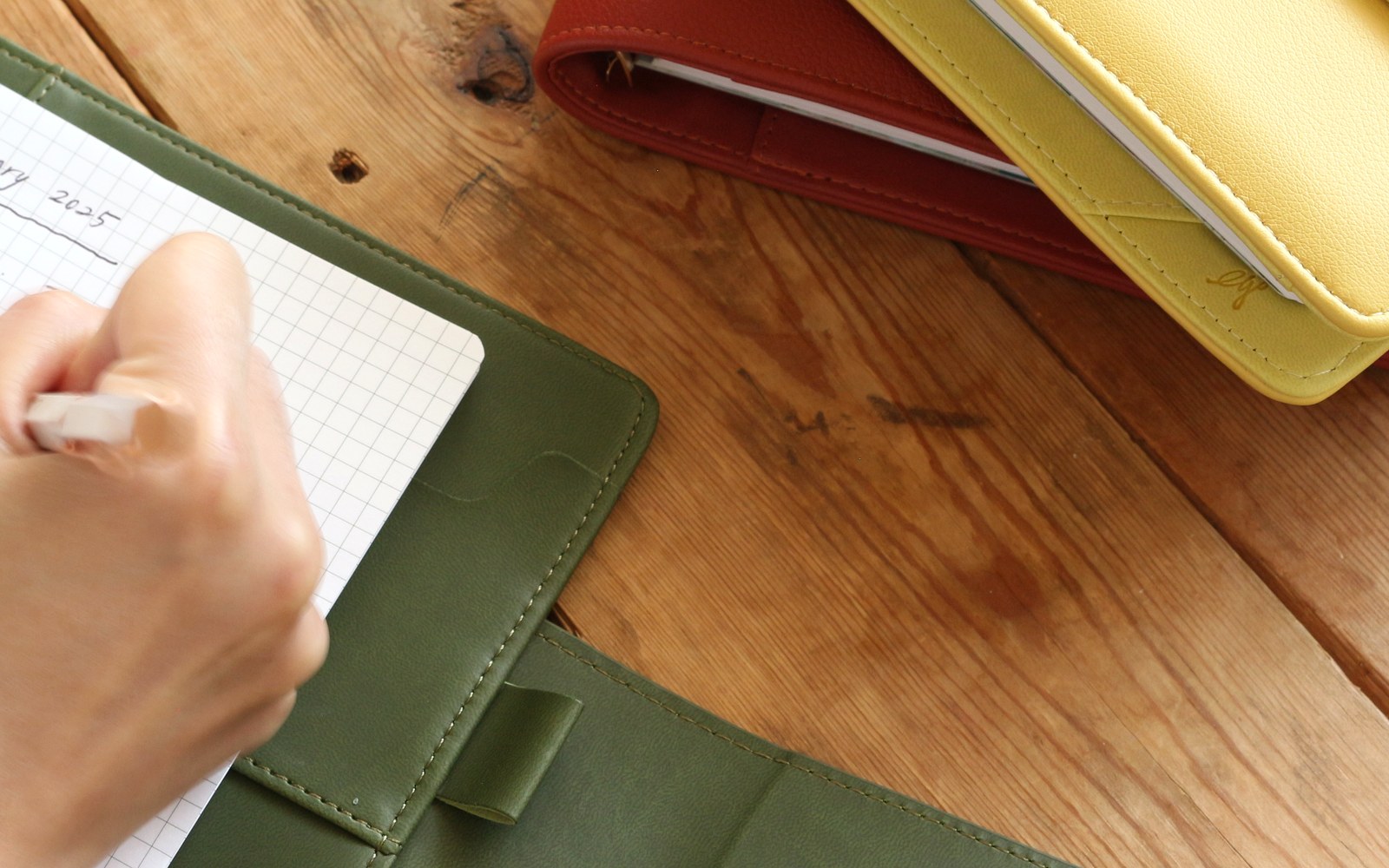 Writing on a grid page in a green EGOSUNNY Belt planner