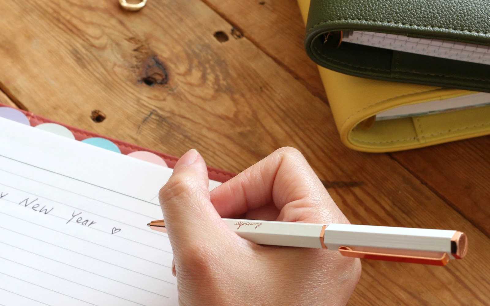 Hand writing in an open EGOSUNNY Belt planner on a wooden table