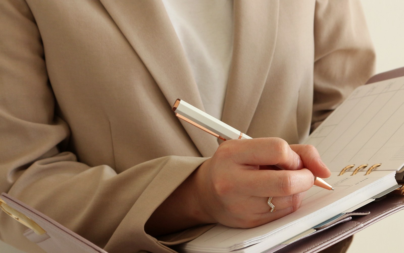 Writing in an open EGOSUNNY Eclair planner while seated