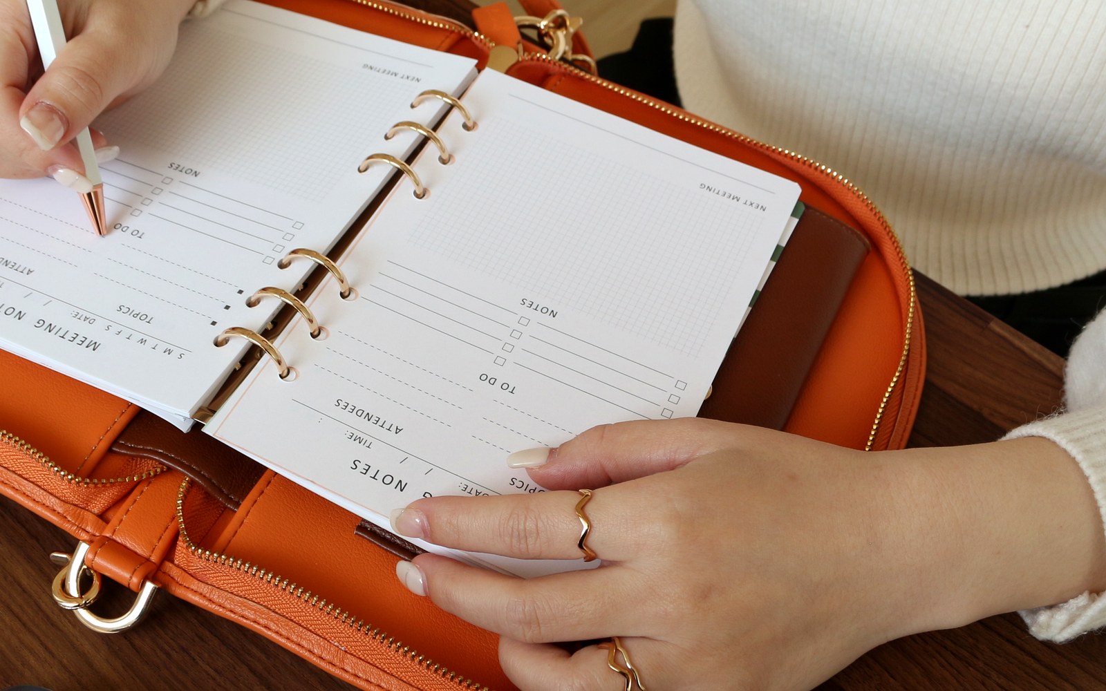 Writing in an orange EGOSUNNY Luna planner at a desk