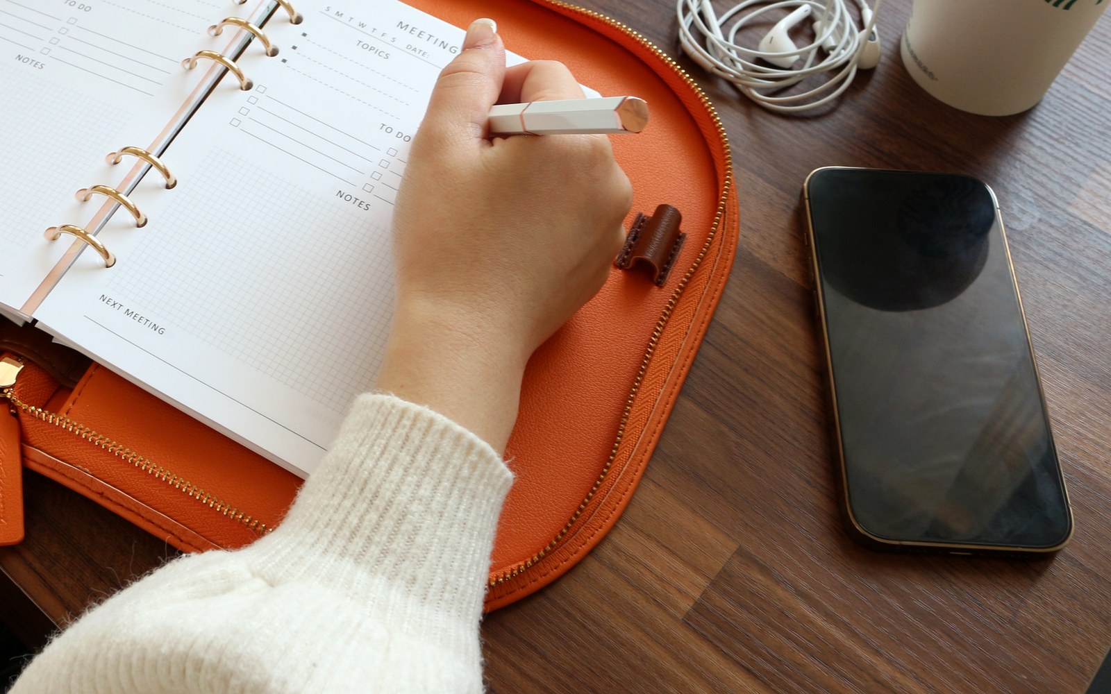 Writing plans in an open orange EGOSUNNY Luna beside a phone
