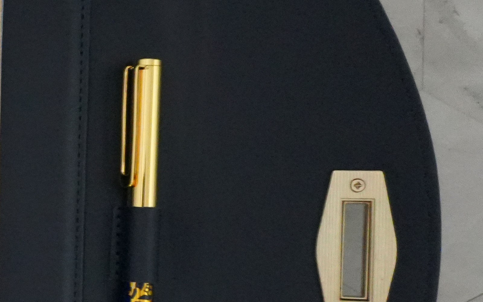 Close-up of a pen and clasp inside an open navy EGOSUNNY Terence