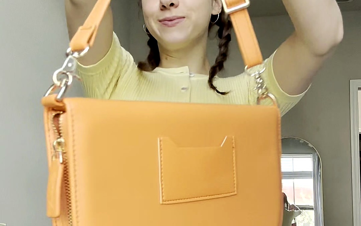 Woman holding up a mustard yellow EGOSUNNY bag-style planner