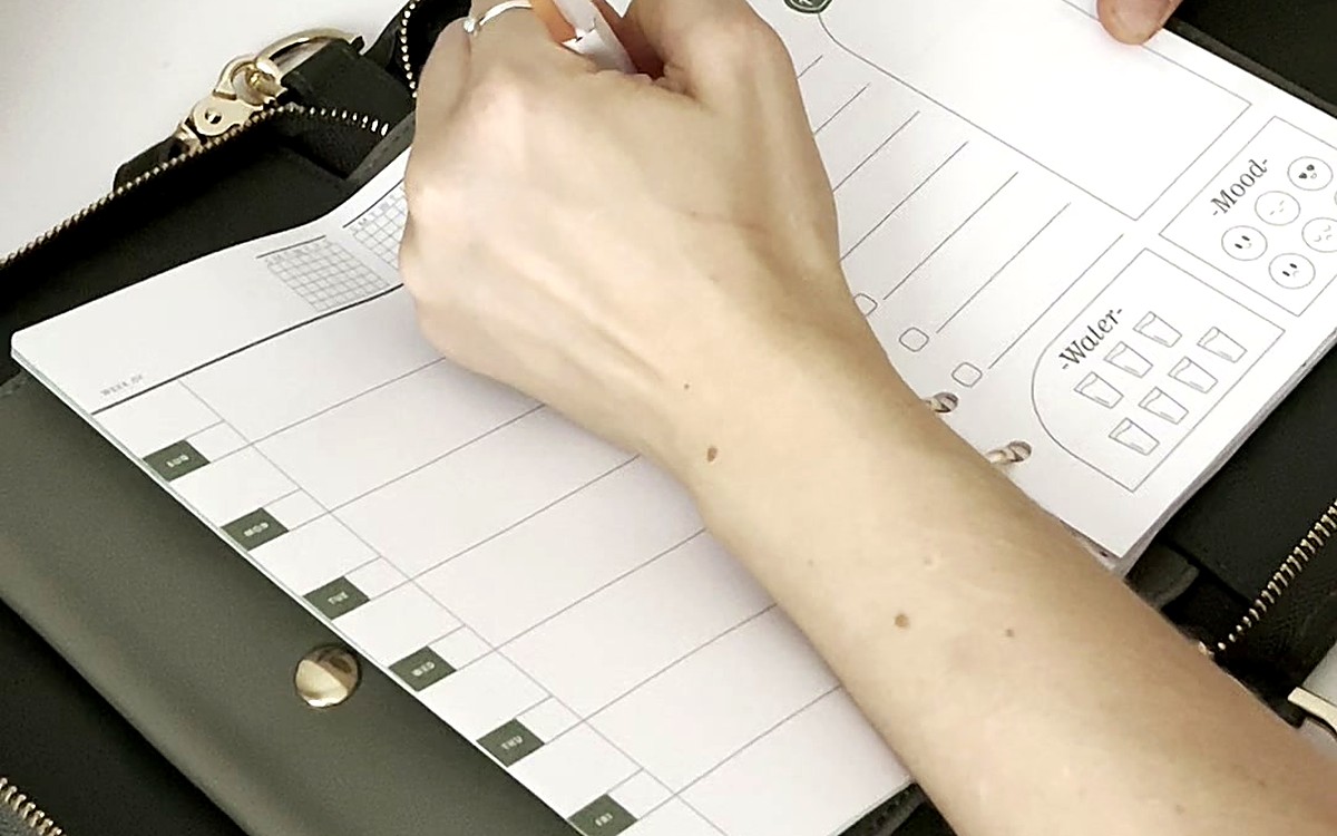 Hand writing inside an open dark zippered EGOSUNNY planner