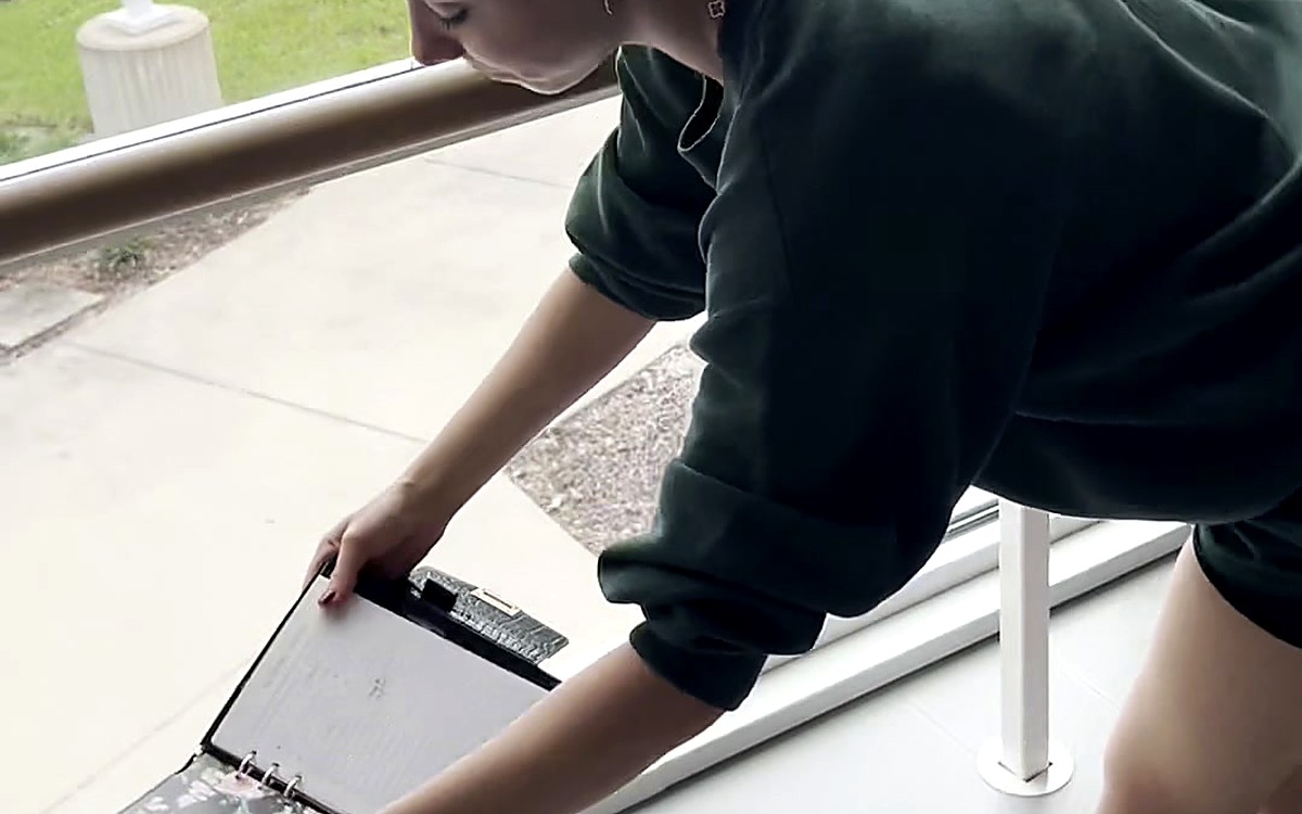 Person on a balcony reaching for a black EGOSUNNY planner
