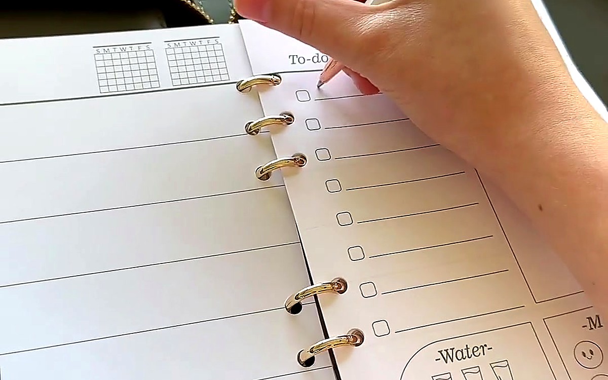 Hand holding a pen above a to-do page with water and mood trackers