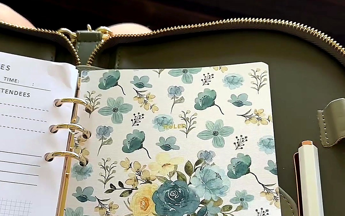 Floral divider and white pen inside an open green planner