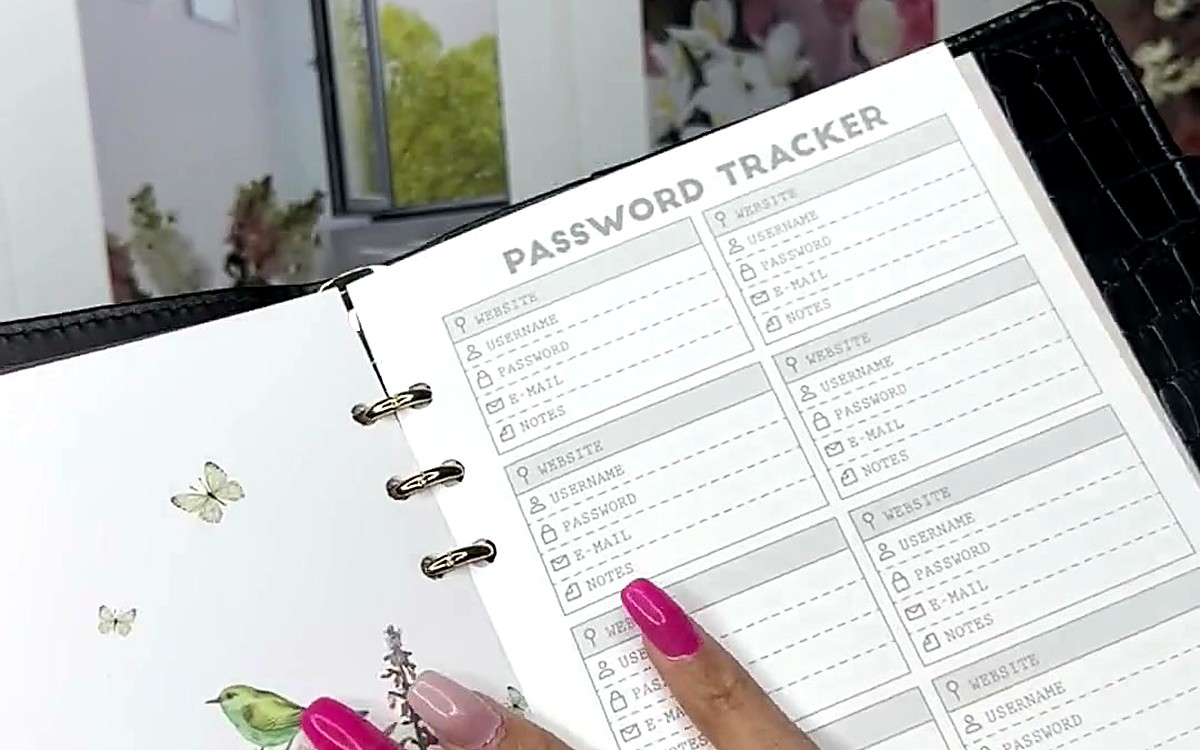 Finger pointing at a tracker page inside a black textured EGOSUNNY binder
