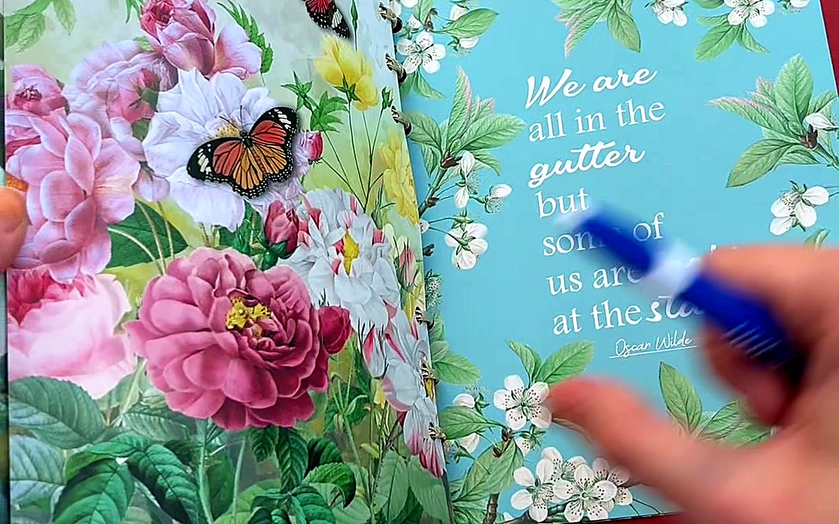 Hands holding an open planner with floral art and a quote page