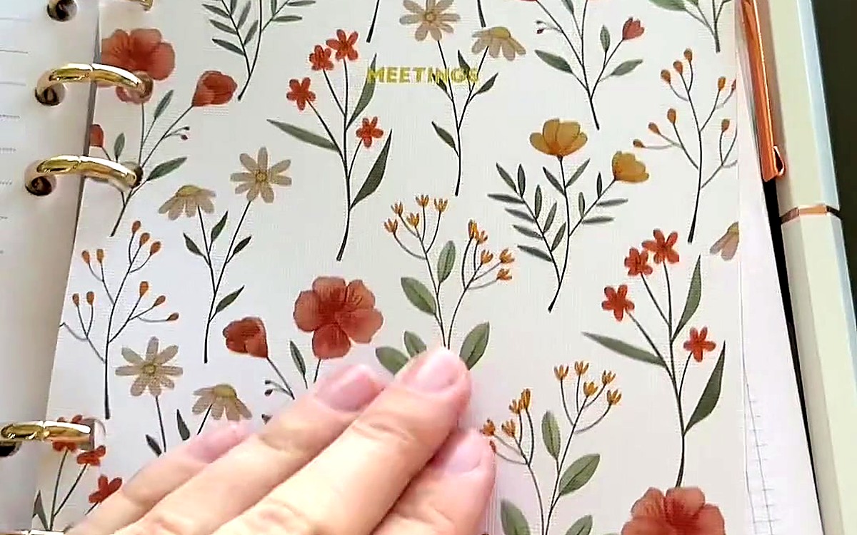 Hand on a wildflower divider inside a gold-ring planner