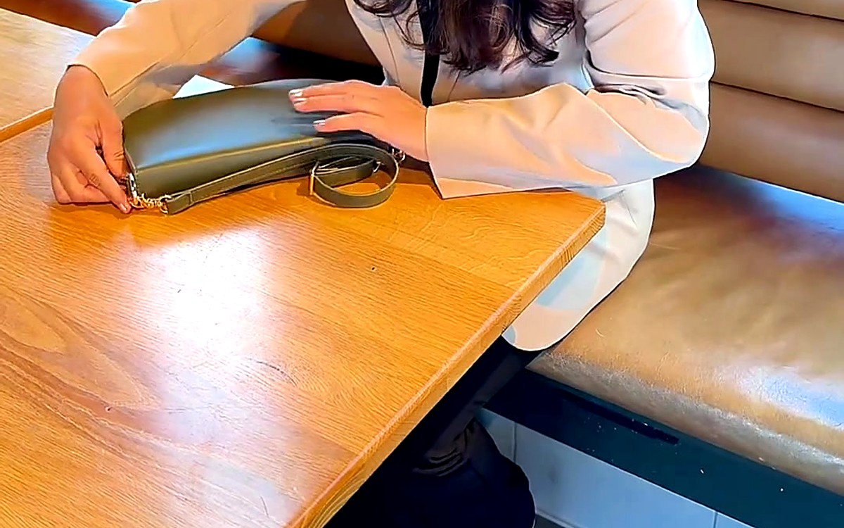 Hands resting on an olive EGOSUNNY pouch at a café table