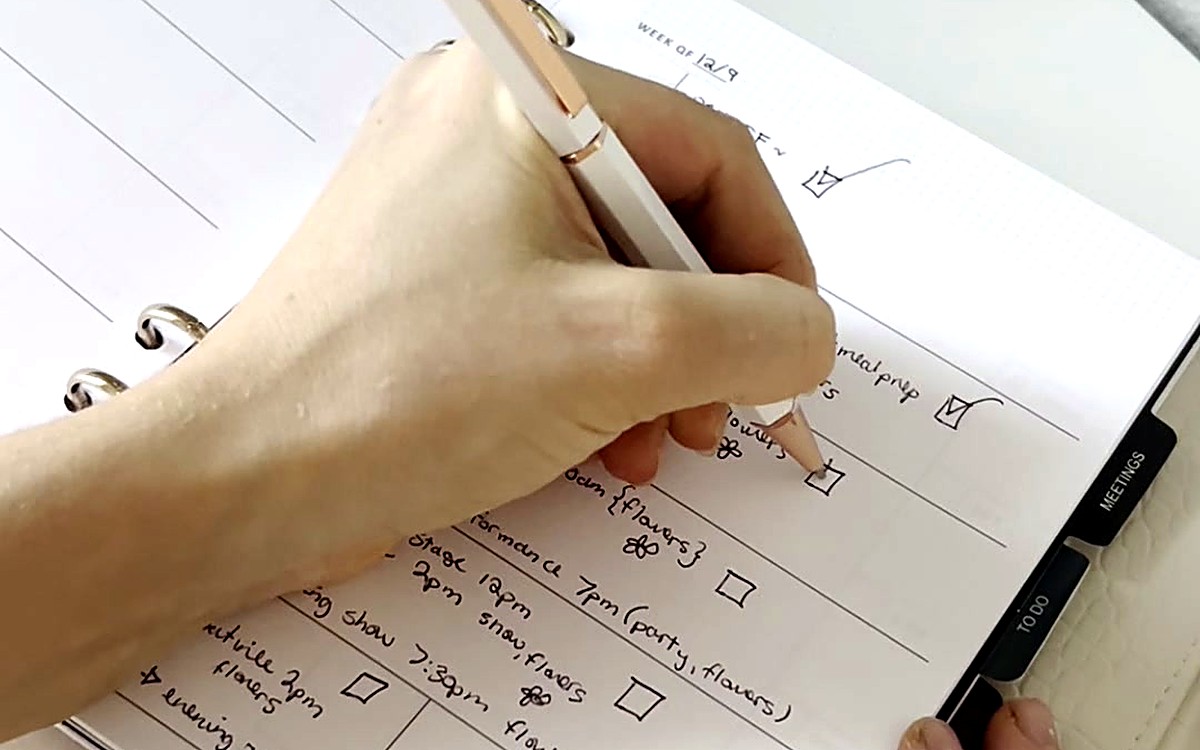Hand checking items on a to-do list in a ring-bound planner