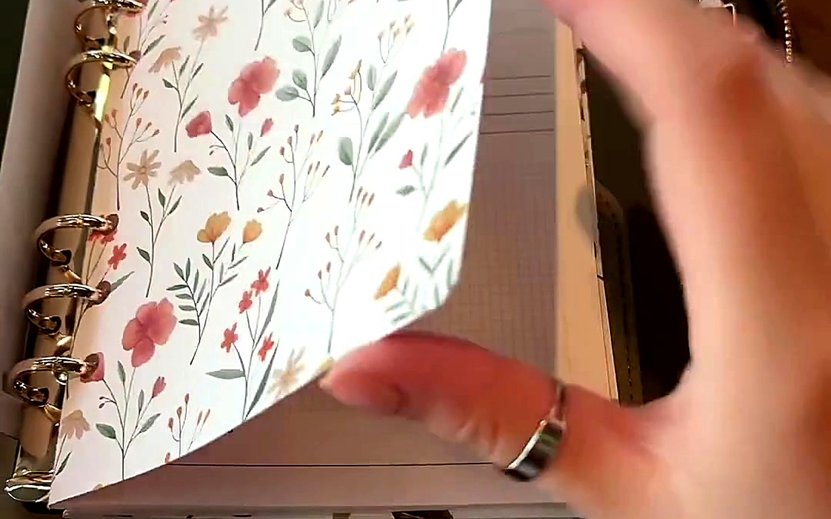 Hand turning a wildflower divider inside a ring-bound planner
