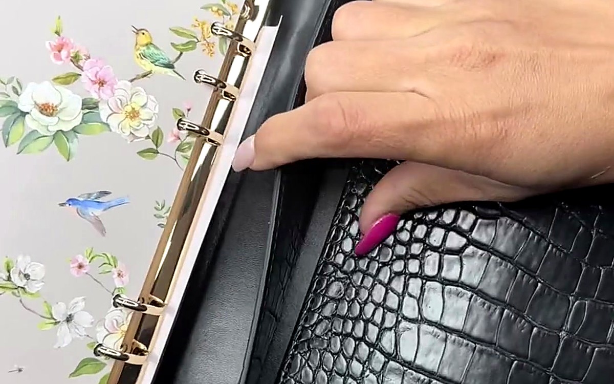 Hands opening a black textured EGOSUNNY binder to a floral divider
