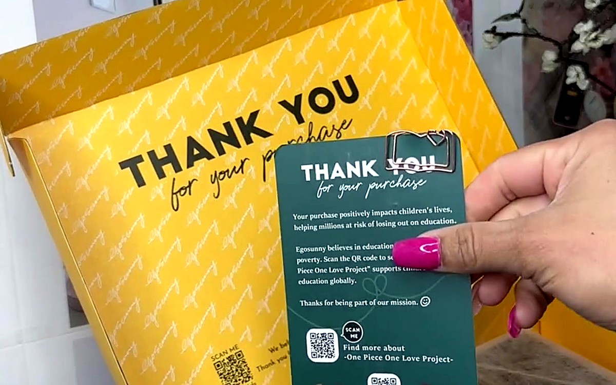 Hand holding a green thank-you card over a yellow gift box