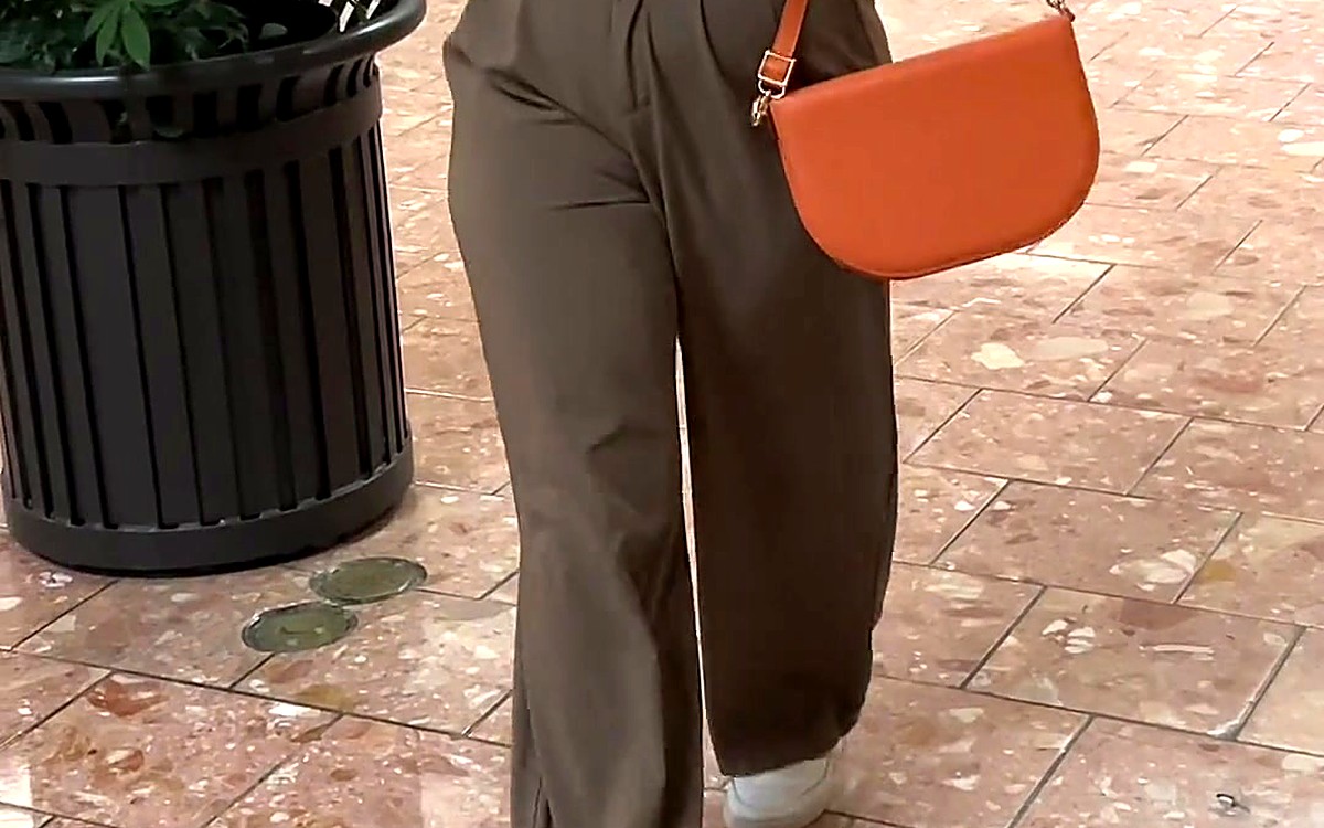 Person walking with a bright orange half-moon EGOSUNNY bag
