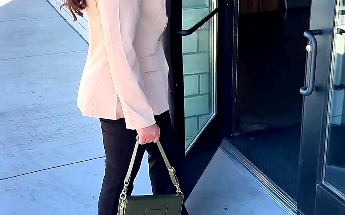 Person stepping through a doorway with an olive EGOSUNNY bag