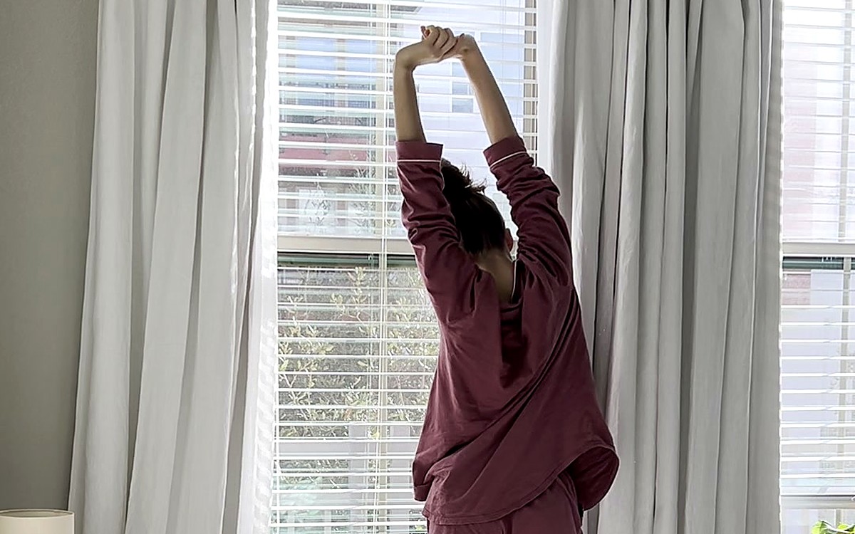 Woman stretching by a bright window at the start of the day