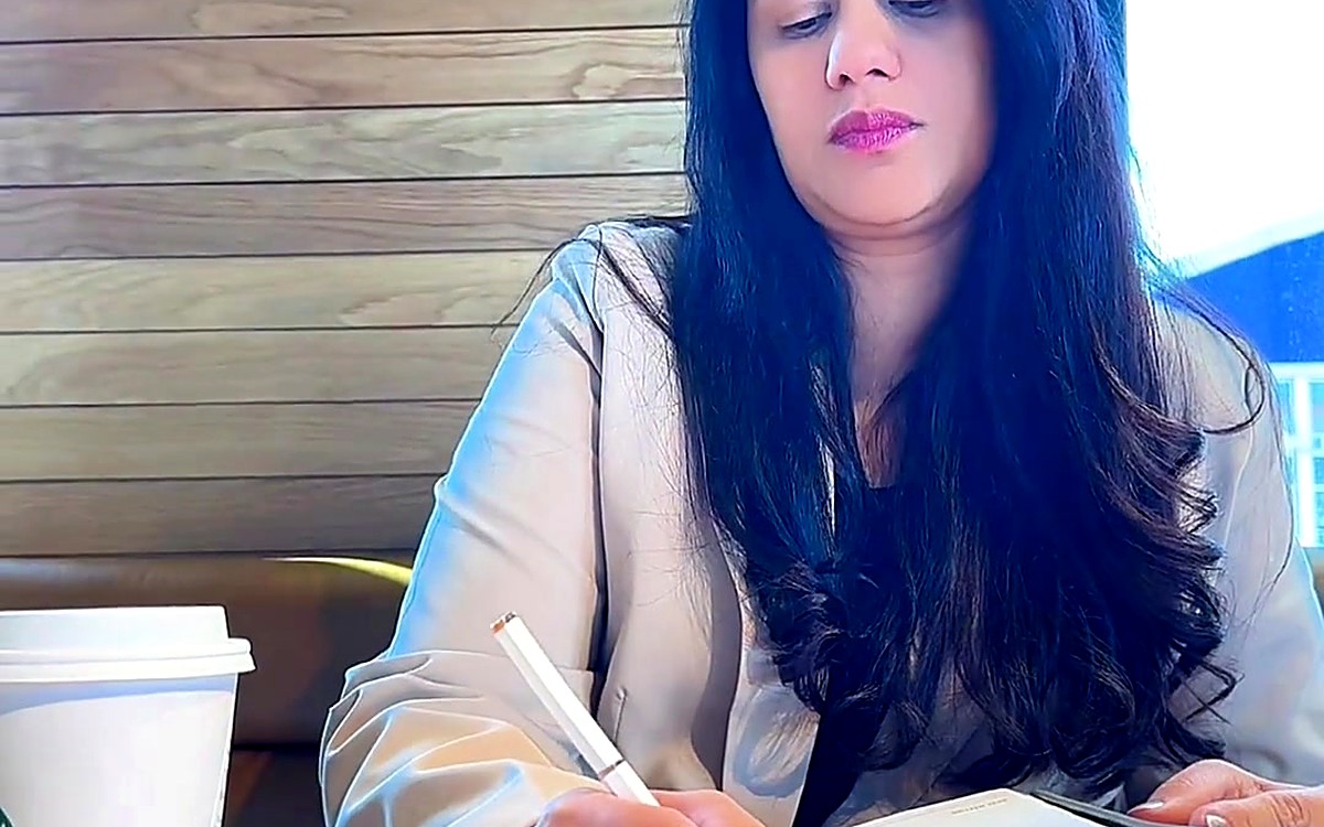 Woman writing in a planner at a café table