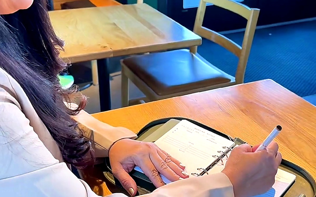 Woman writing in a planner at a café table