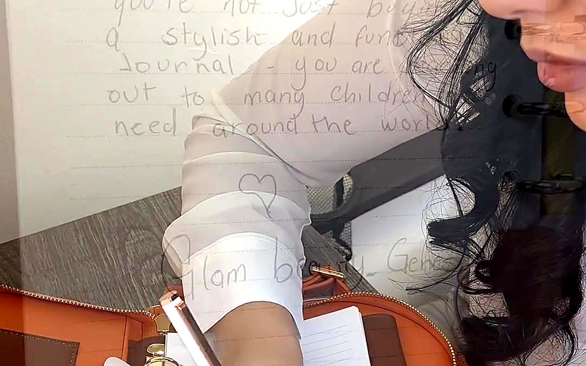 Woman writing in a planner in front of a handwritten board