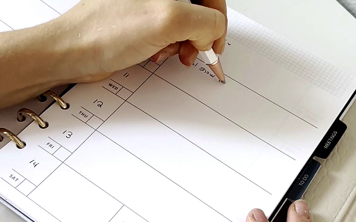 Hand writing on a schedule page in a ring-bound planner