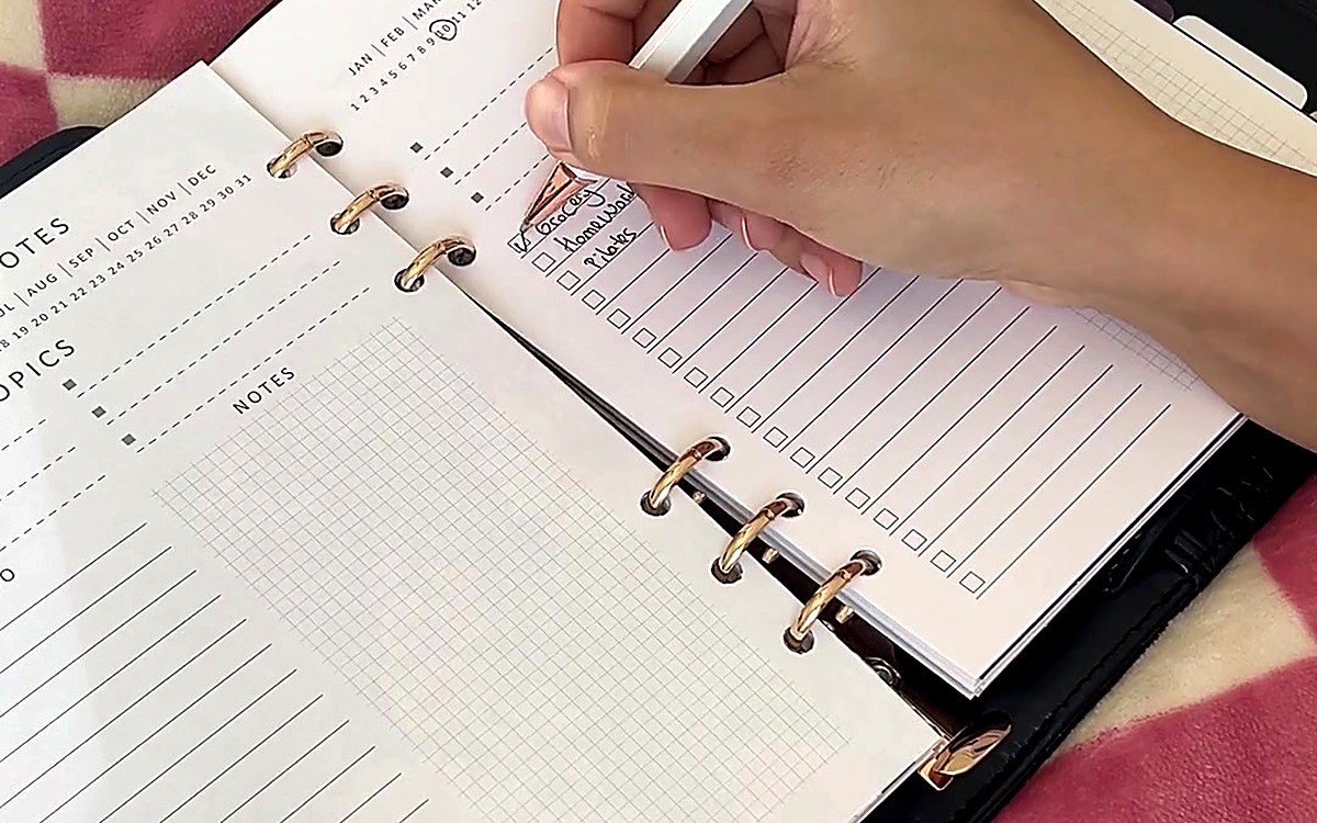 Hand writing in an open planner with ring binding