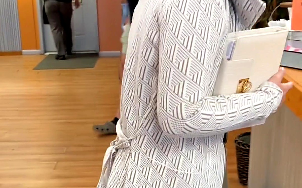 Woman in a white cardigan holding a planner indoors