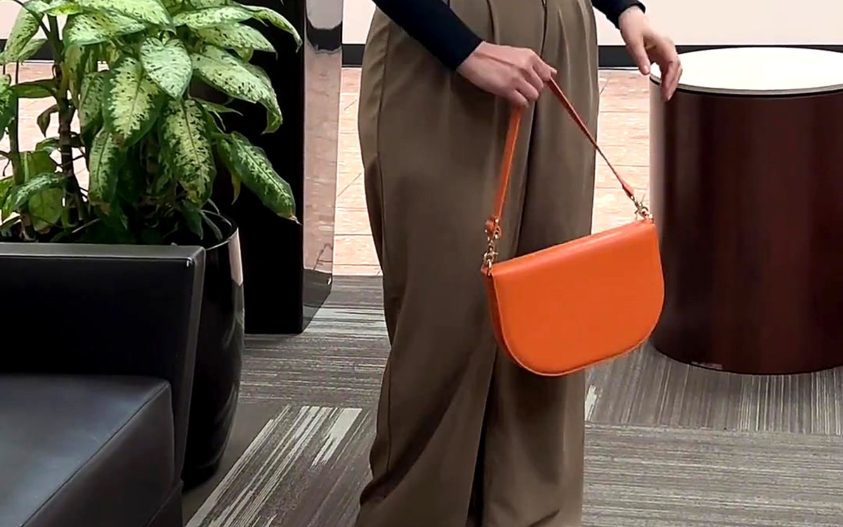 Woman carrying an orange EGOSUNNY bag-style planner by its strap