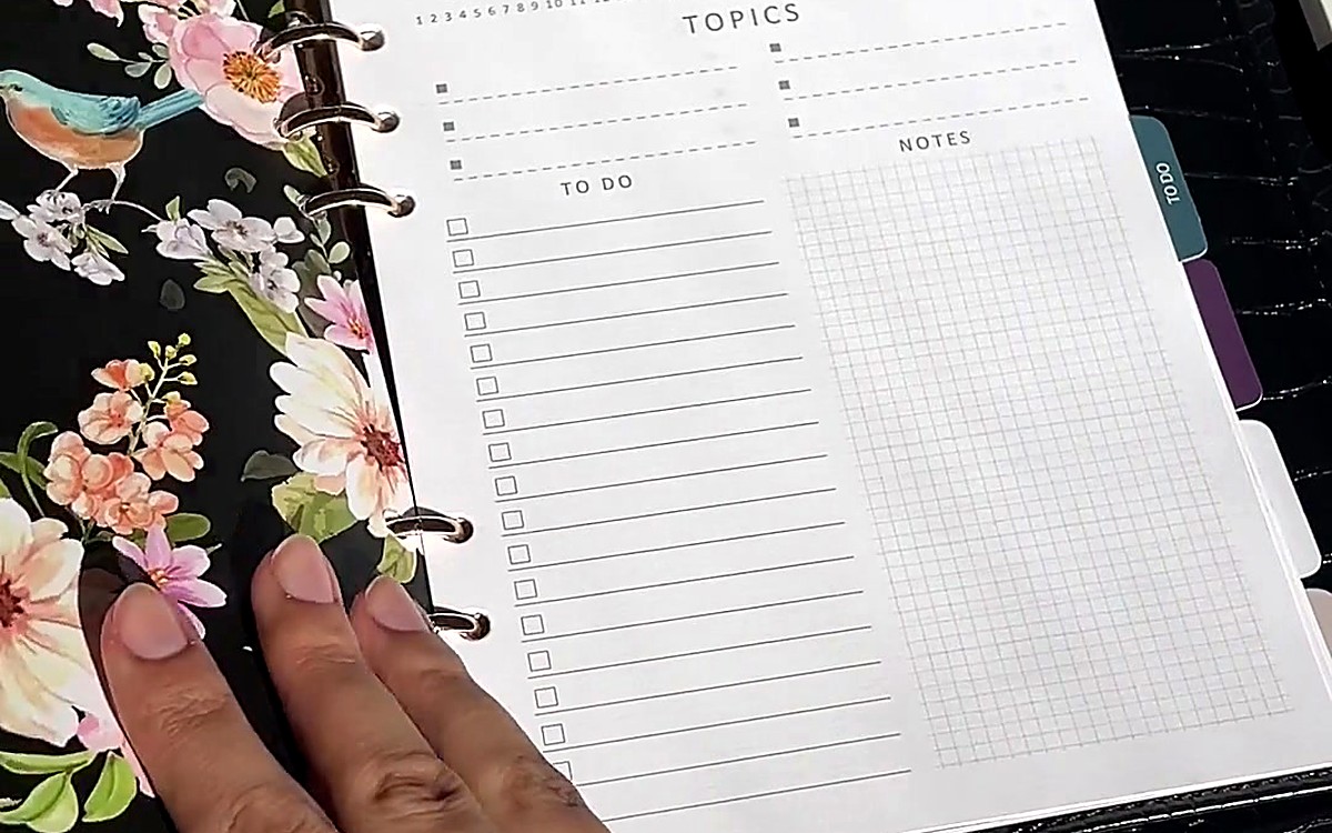Hand resting on a floral planner page with checklist lines
