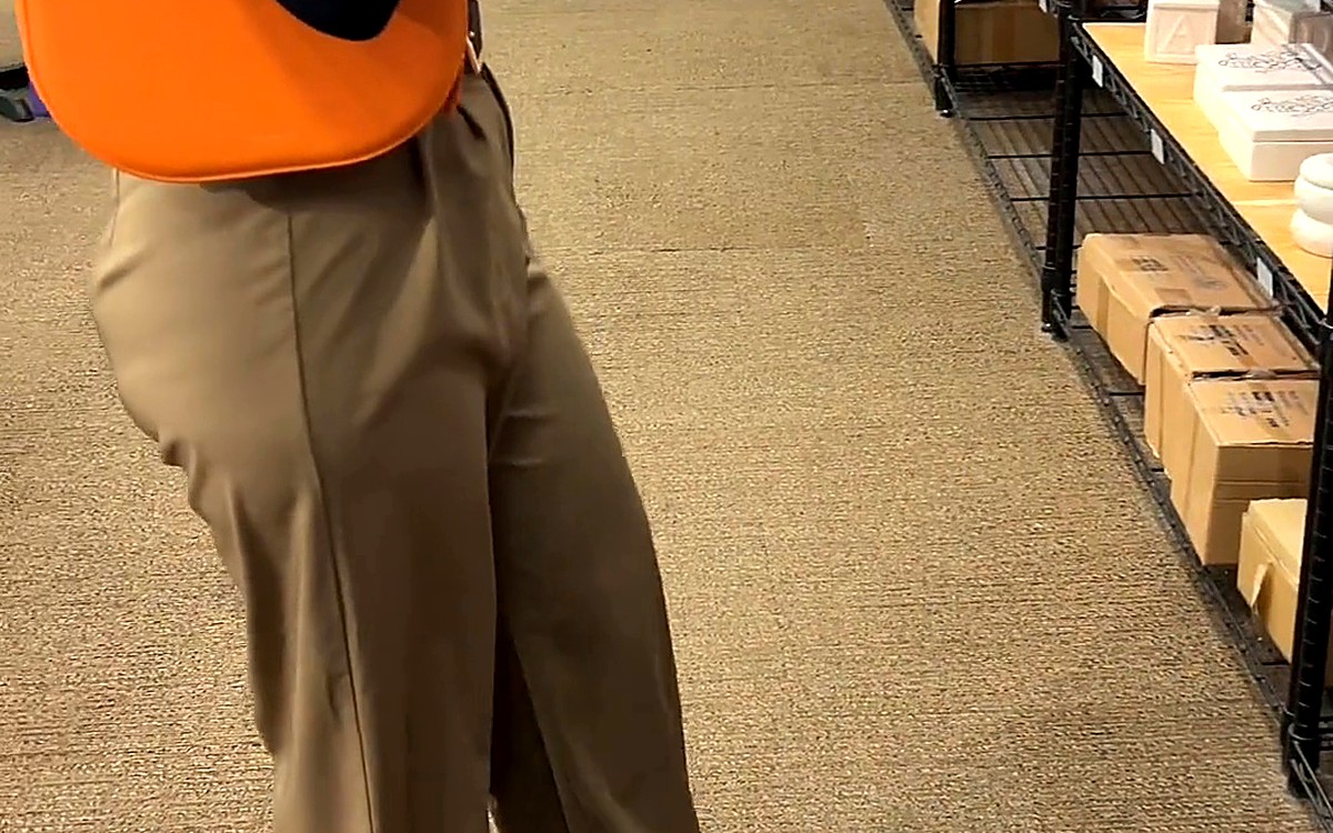 Woman walking through a bookstore with an orange bag on her shoulder