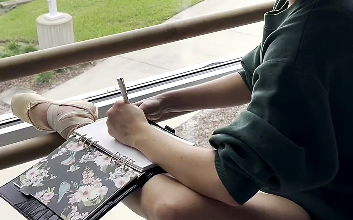 Person sitting outdoors writing in a planner
