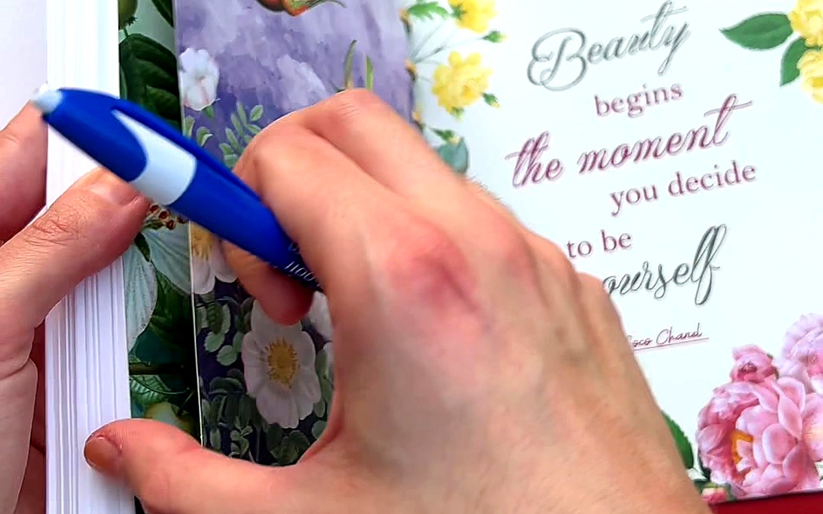 Hand holding a pen over a quote card in a planner