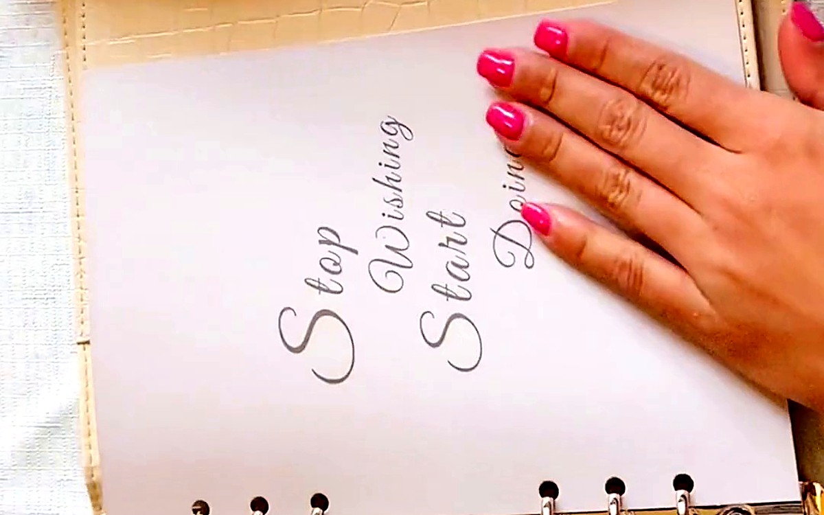 Hand on an insert page that reads Stop Wishing, Start Doing