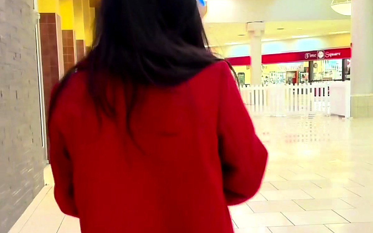 Woman in a red sweater walking in a bright hallway