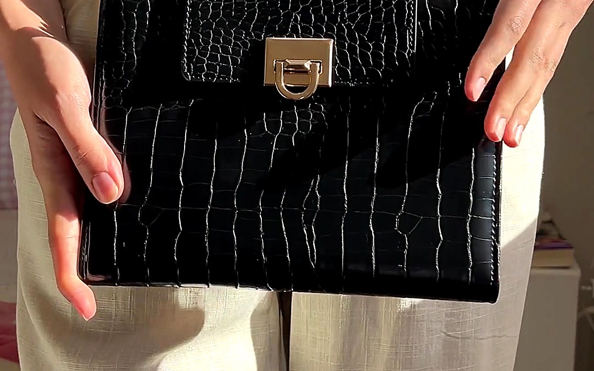 Hands holding a black textured EGOSUNNY planner with a gold clasp
