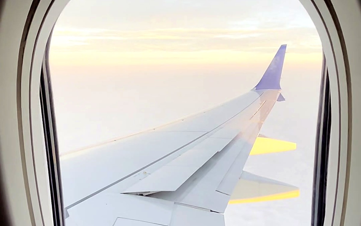 Airplane wing seen through a window at sunset